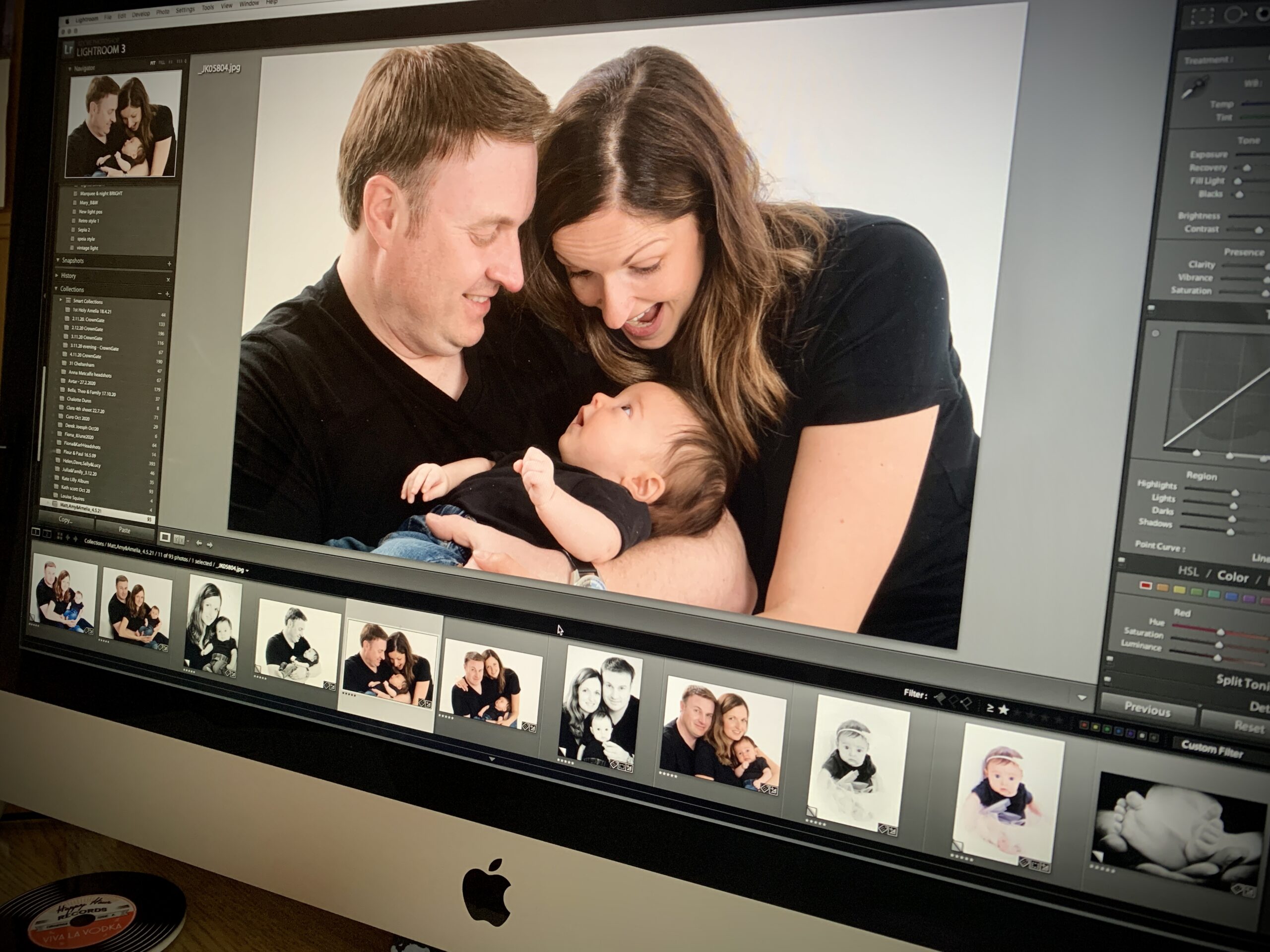 Beautiful family portrait in a studio setting, featuring parents lovingly cradling their newborn baby, surrounded by soft lighting and warm smiles