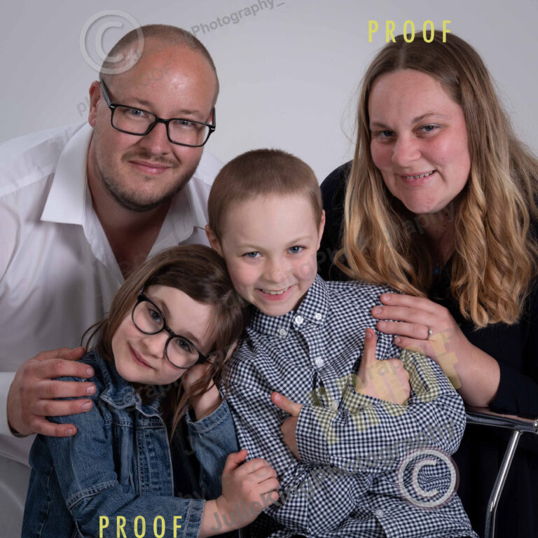 Happy family of four in a Bromsgrove photography studio, dressed in coordinated outfits for a classic portrait.