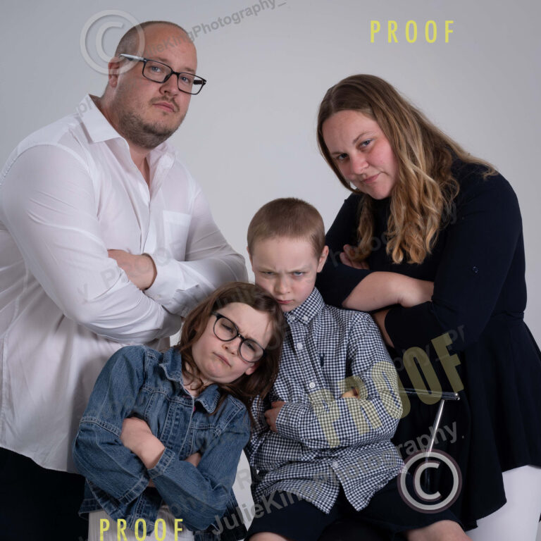 Happy family of four in a Bromsgrove photography studio, dressed in coordinated outfits for a classic portrait.